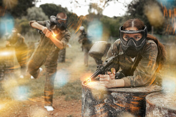 Fototapeta premium Paintball players of one team in camouflages and masks aiming with gun in shootout playing field