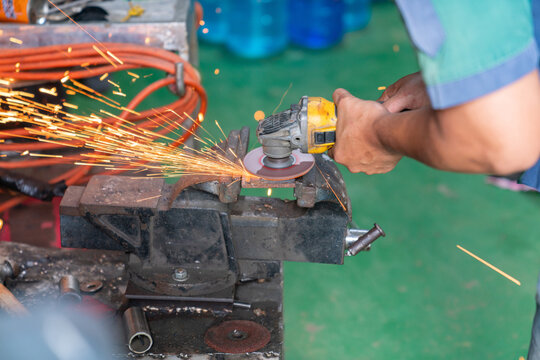 Worker using electric grinding matal and sparks.