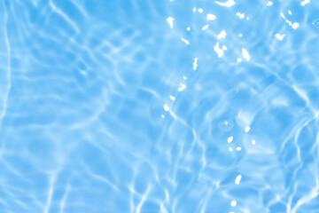 Blue water with ripples on the surface. Defocus blurred transparent blue colored clear calm water surface texture with splashes and bubbles. Water waves with shining pattern texture background.