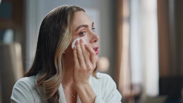 Calm lady cleaning face in bathroom closeup. Confident woman holding cotton pad
