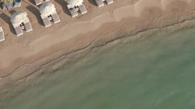 4K Aerial Footage of Sandy Greek Island Beach with Crystal Clear Water. Birds Eye View of Beach Umbrellas.