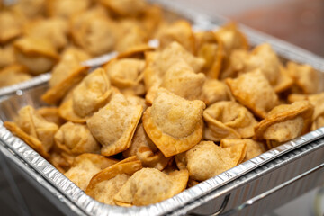Chinese cream cheese wontons served in a silver catering container delivered for an event. Crispy crab rangoon