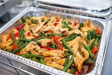 Stir fry chicken, sweet peppers and green beans. Served in a silver catering container delivered for an event