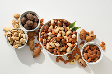 Various nuts in white bowls on a white background