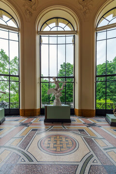 A grand sculpture gallery in Petit Palais, Paris, beautifully illuminated by natural light streaming through large arched windows
