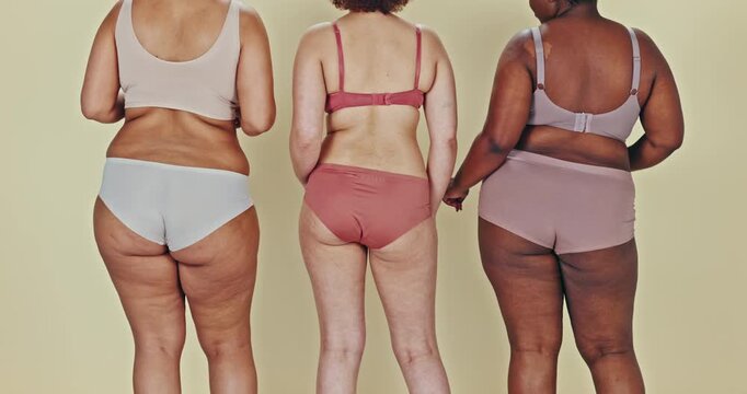 Dancing, body positivity and women butts in underwear in a studio for self love celebration. Freedom, diversity and bum of female people moving to music with confidence together by green background.