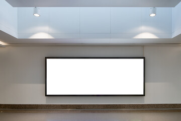 Background texture of a large, blank white billboard mounted on a wall in a modern, indoor room, hall or corridor with a high ceiling and recessed lighting. Copy space for ad design.