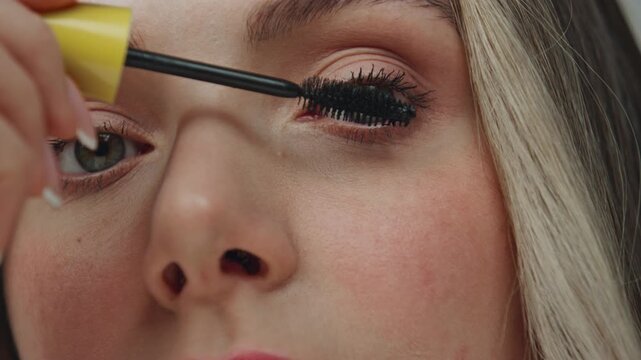 Model face applying mascara at domestic place closeup. Woman looking camera