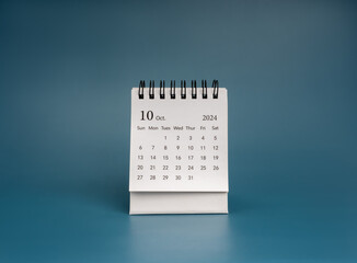 Front view of white October 2024 page, desk calendar for plan and reminder isolated on dark blue background. Simple small minimal calendar 10th month, for business agenda and schedule concept.