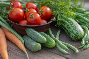 Fresh vegetables: tomatoes, dill, cucumbers, carrots, beans on a wooden background