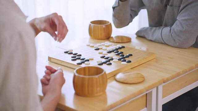 Close up of young men play board game Go during competition in community. 