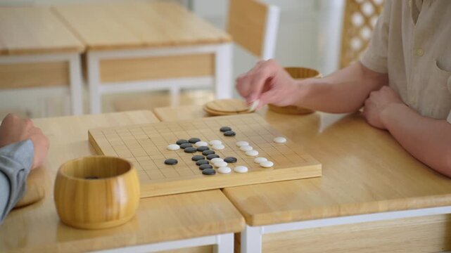 Close up of young men play board game Go during competition in community. 
