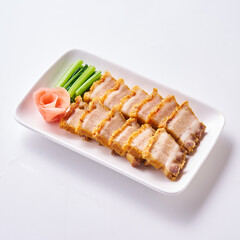 Roast pork and crispy pork with Chinese sausage on a white plate with side vegetables and pickled ginger.