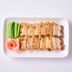 Roast pork and crispy pork with Chinese sausage on a white plate with side vegetables and pickled ginger.