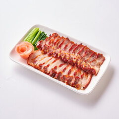 Roast pork and crispy pork with Chinese sausage on a white plate with side vegetables and pickled ginger.