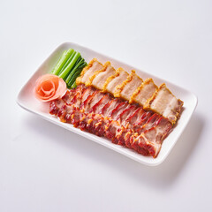 Roast pork and crispy pork with Chinese sausage on a white plate with side vegetables and pickled ginger.