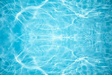 Blue water with ripples on the surface. Defocus blurred transparent blue colored clear calm water surface texture with splashes and bubbles. Water waves with shining pattern texture background.