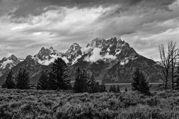 Black and white image of storm clouds over the Grand Teton Mountain and meadow landscape in Jackson Valley, Grand Teton National Park, Wyoming, USA.