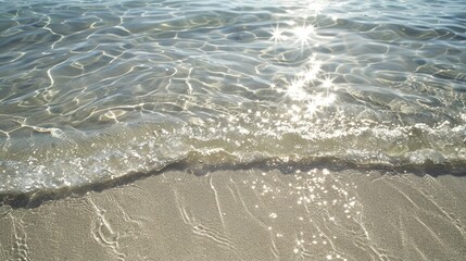 The warm sun reflects on the crystal clear water, creating sparkles as waves gently lap against the pristine white sand beach