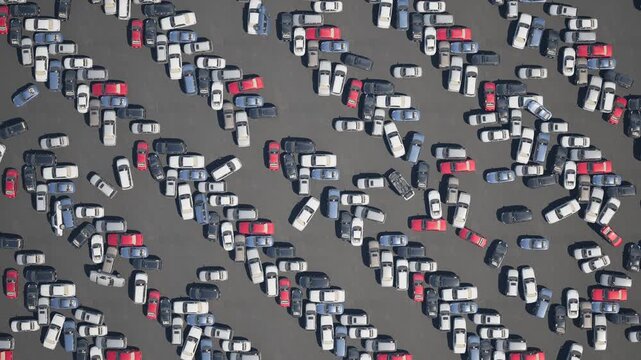 Drone footage of an abandoned parking lot filled with brand-new vehicles.
