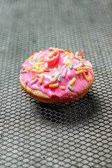 A pink mini donut with sprinkles on top