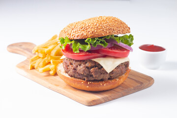 Homemade delicious hamburger with beef, onion, tomato, lettuce and cheese. Fresh burger close up on wooden rustic table with potato fries. Cheeseburger. Burger.