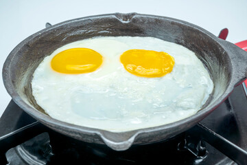 A pan with sunny side up eggs in it on a stove
