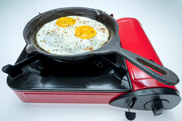 A pan with sunny side up eggs in it on a stove