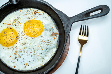 A plate of sunny side up eggs and a fork on a table