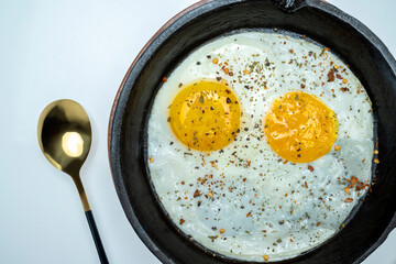 A plate of sunny side up eggs with a spoon next to it