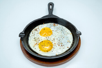 A pan with sunny side up eggs and some pepper on top