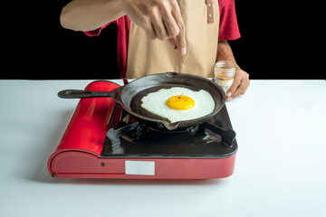 A man is cooking an sunny side up egg in a pan on a stove