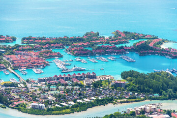 A stunning aerial view of a tropical island resort with a beautiful marina filled with yachts and boats. Seychelles - tropical travel destination