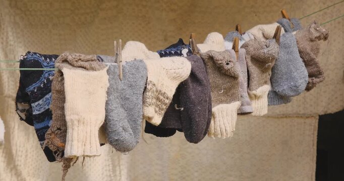 old peasant woolen socks on rope with old wooden hooks with an old carpet in the background