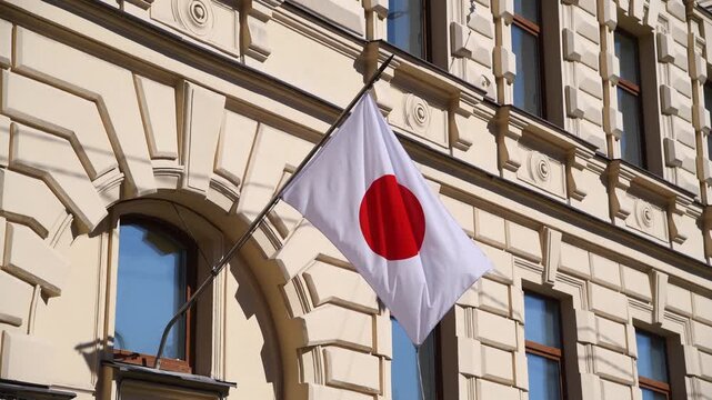 lose-up view of Japanese national flag located on building wall and swaying on the wind in a sunny summer day. Real time video. Soft focus. National symbols theme.