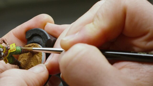 Artist in Studio Painting Miniature Fantasy Figure Model Character Delicately with Fine Paint Brush with Details on Fingers 4K