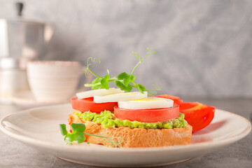 Toast with avocado, boiled egg, tomatoes and microgreens on a plate. Keto diet food.