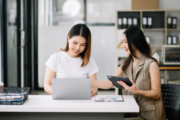 Obraz premium Two Asian businesswoman discuss investment project working and planning strategy with tablet laptop computer