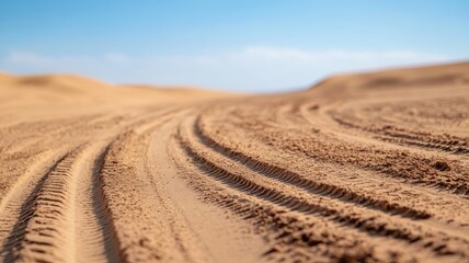 Close-up of dusty desert road with tire tracks and footprints.