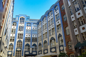 The façade of the house with large windows and a blue sky above it. Hackesche Hoefe is a notable...