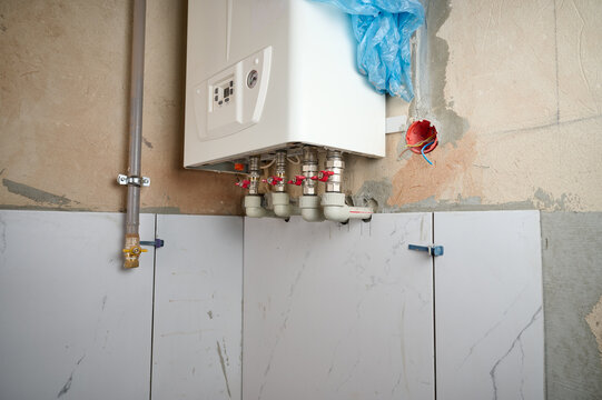 Double-circuit gas boiler on the wall. Plumbing connections and pipes of the domestic heating system. Regulation pipe from water heater. Valve.