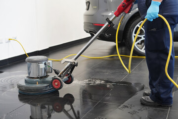 Close-up shot a worker washing office floor with cleaning machine