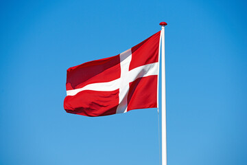 Flag, blue sky and denmark with symbol of country, scandinavian or danish state with red and white cross. Wind, pole or colorful representation of Dannebrog, history or nation in Copenhagen or Europe