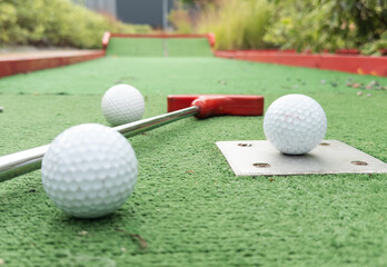 colorful golf putters with golf balls on synthetic grass