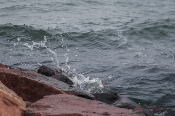 Close-up of splash of a small wave crashing on rocks.