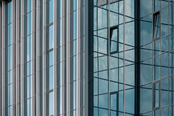 empty glass windows of a modern building with a reflection of the sky in the glass