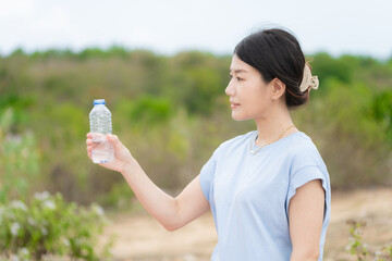 自然の中でペットボトルの水を飲む日本人女性