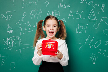 Little happy school girl 7-8 years old pony tails wear white shirt uniform show red lunch box going...