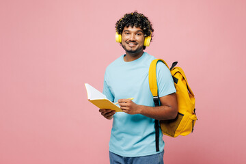 Young Indian boy student wear blue t-shirt casual clothes headphones backpack bag write down in...
