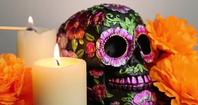 A skull and orange marigolds are highlighted by the flame of a lit match, setting a somber tone for D&iacute;a de los Muertos festivities. Day of the dead holiday